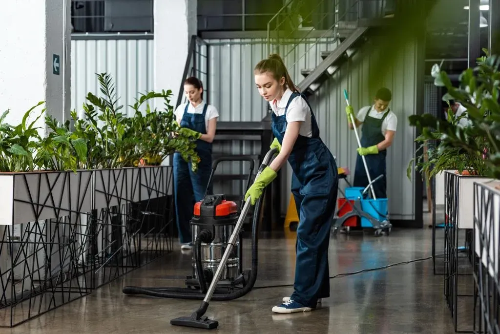 Reinigungsteam in Arbeitskleidung bei der Unterhaltsreinigung eines hellen Gebäudes